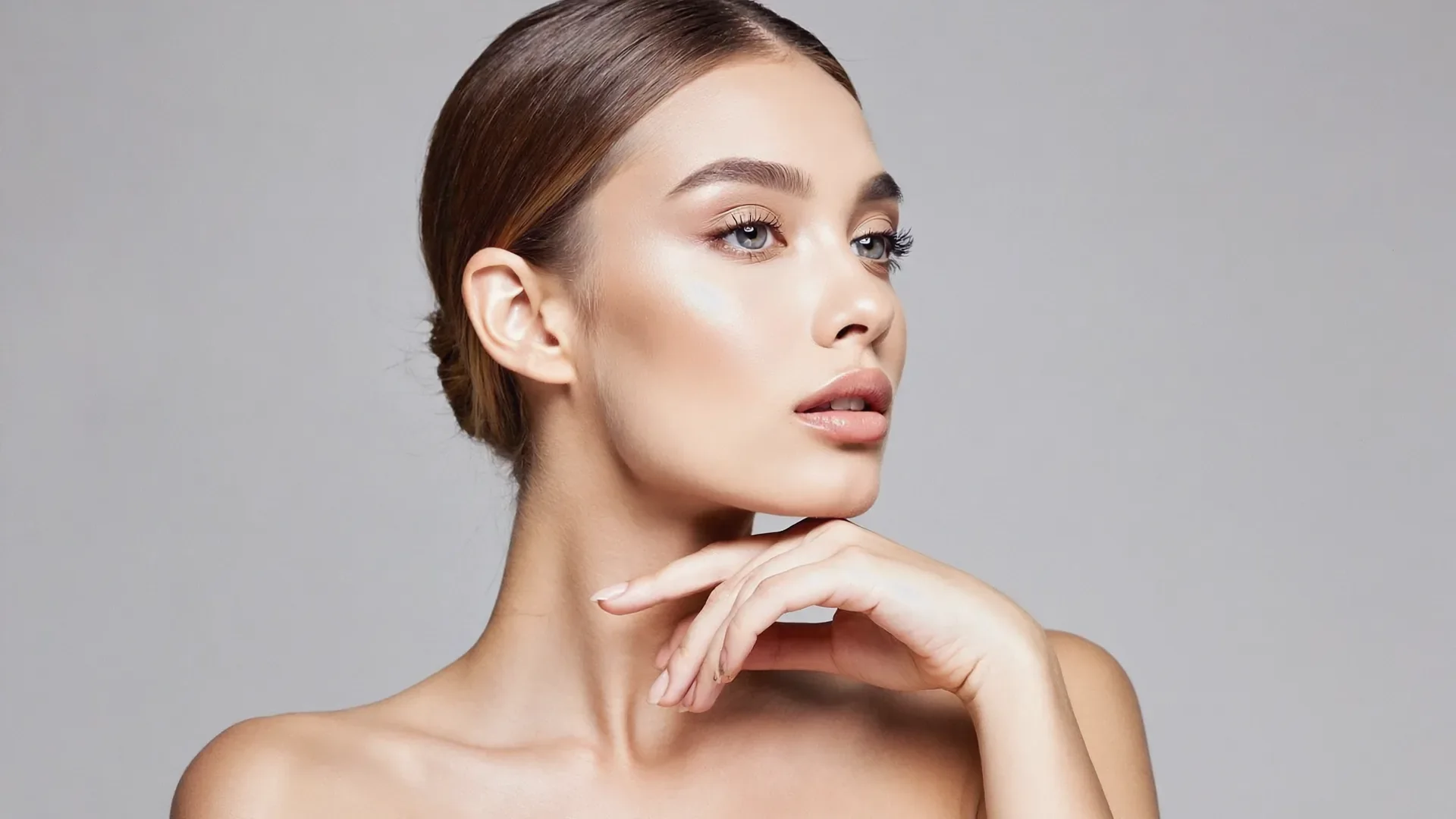 Elegant woman in profile gently touching her jawline, evoking the advanced treatment areas of the lower face and neck